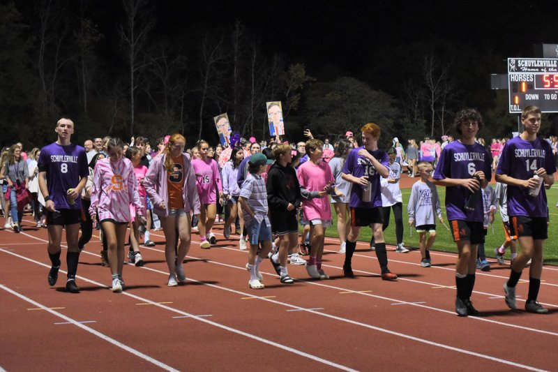 Schuylerville students, staff, and community members participate in a ‘glowstick walk’ at halftime of the varsity boys soccer game on Tuesday as part of the ‘Kickin’ Out Cancer’ fundraiser in honor of longtime teacher Dave Mehan (Photo by Super Source Media Studios).