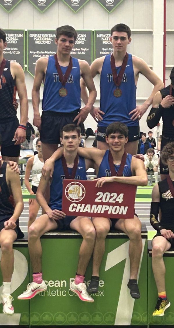 Saratoga Springs High School runners Jacob Bernd, Luke Dacey,  Owen Blaisdell, and Thomas Isenovski pose on the first-place podium after winning the 4x800 meter relay finals at the  NYSPHSAA championships last weekend.
