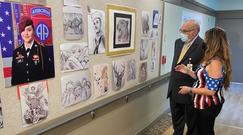 Chief Executive Officer of The Wesley Community Brian Nealon (left) and Wesley Health Care Center LPN Mary Jenks (right) discuss the artwork of U.S. Army Specialist Abigail Jenks at the Wesley Health Care Center on Wednesday, Sept. 8. 