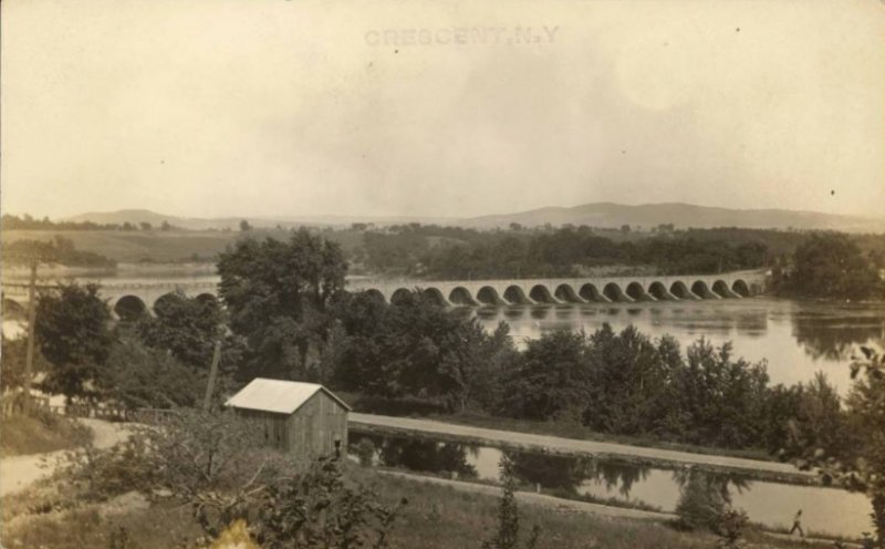 Unmailed photo postcard showing the 26-arched aqueduct carrying the Erie Canal over the Mohawk River at Crescent, Saratoga County. The image courtesy of the Madden collection of the Canal Society of New York State collection. 