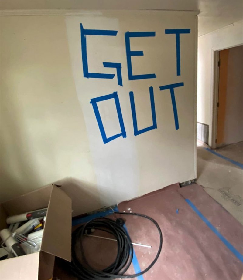 Blue painter’s tape fixed to one of the walls inside a home under renovation in Geyser Crest. The message continues along a second wall to include a racial slur.