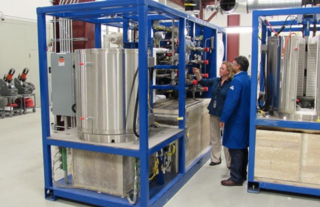 GE Fuel Cells General Manager Johanna Wellington and a team member inspect a test stand of fuel cell stacks. 