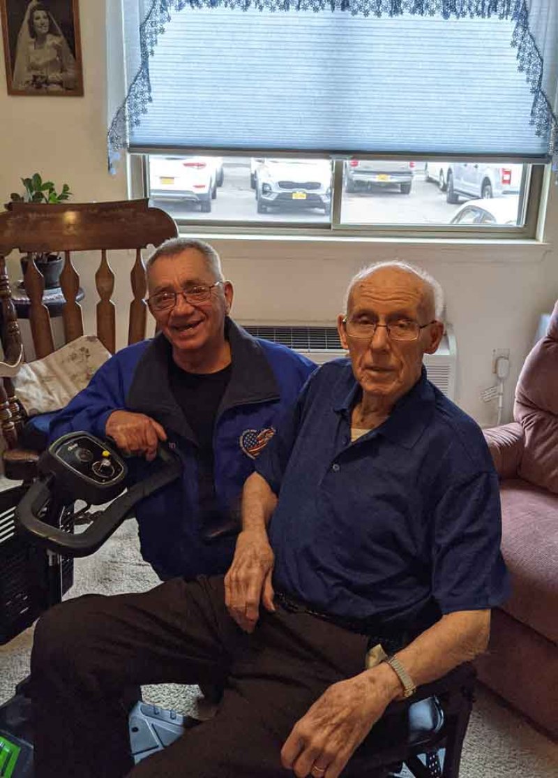 Cliff Seguin chairman for Operation Adopt a Soldier (left) and George Habernig Sr. (right) sits on a scooter that OAS donated to him.
