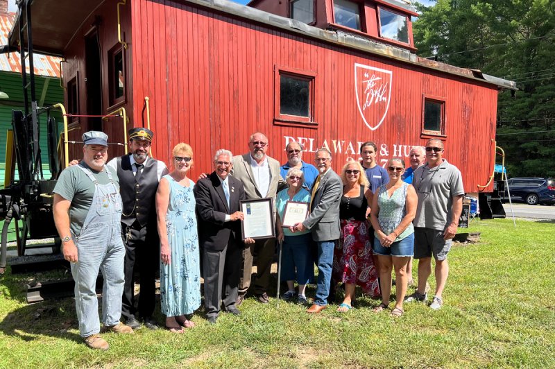 Pictured left to right are: Brad Peterson and Hal Raven of Saratoga Corinth &amp; Hudson Railway; Town Clerk Karen Dowen; NYS Senator James Tedisco; Town Supervisor Kevin Veitch; Shirley Hammond; wife of Glen Hammond; Mark Hammond, son of Hammond and Malta Town Supervisor; as well as family members Sandy Hammond, Brenda Cameron, (back row) Duane Hammond, Ian Hammond and Graeme Cameron; and Town Councilman Mike Gyarmathy.