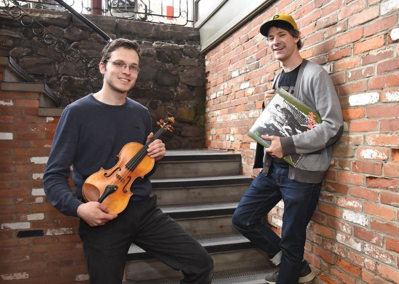 Thomas Dunn holds a violin, Jason Planitzer clutches a record album outside of their new store on Broadway that features a collaborative effort of their respective businesses, Sixth Generation Violin and Off-Track Records. Photo by SuperSource Media. See Story pg. 9